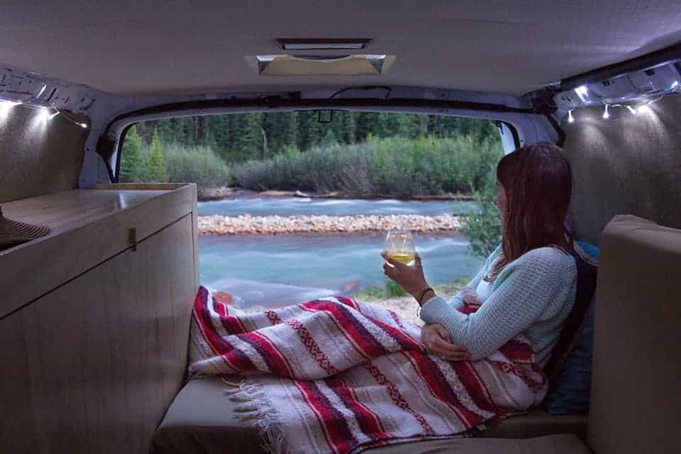 Women Drinks Wine While Looking Out At A Stream In Her DIY Camper Van Conversion Women Drinks Wine While Looking Out At A Stream In Her DIY Camper Van Conversion