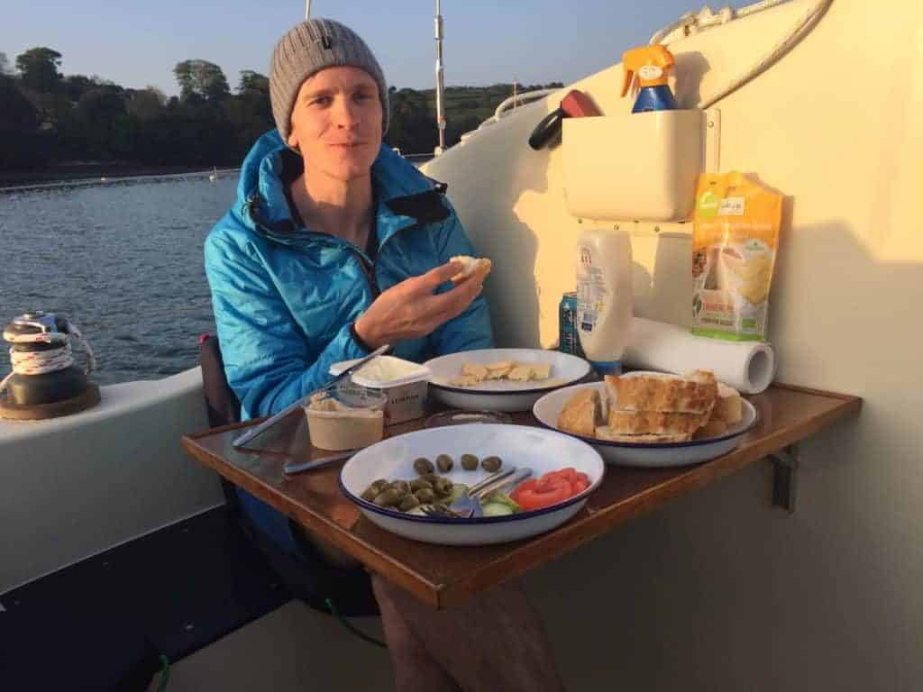 Ryan eats a meal on the deck of their sailing catamaran in the Mediterranean sea