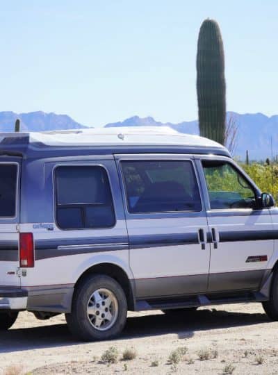 Chevy Astro van camper in the desert with woman on back bumper
