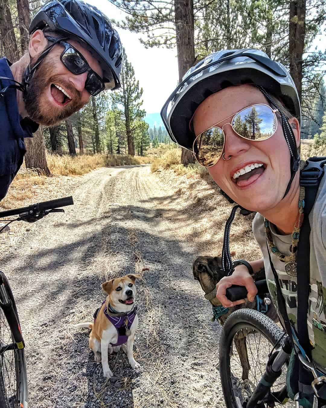 John and Jayme riding their bikes on a country road with their dog