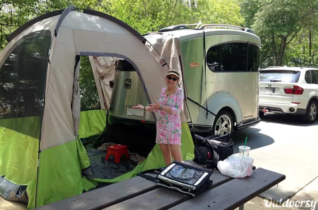 Woman standing near a tent outside an Airstream trailer rental
