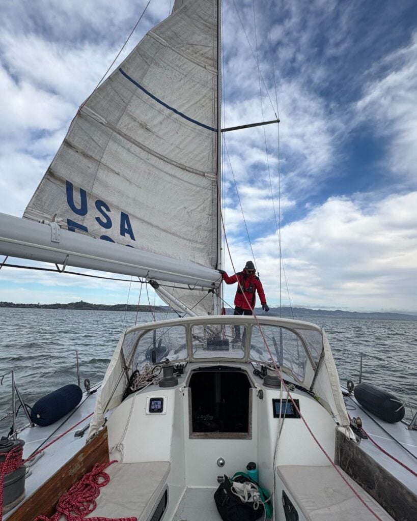 man standing on the bow of a sailboat