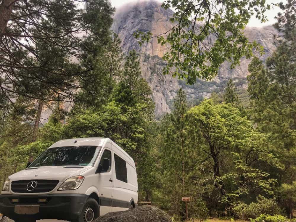 The Rabbit Hole Sprinter Camper Van with forest and mountain in background.