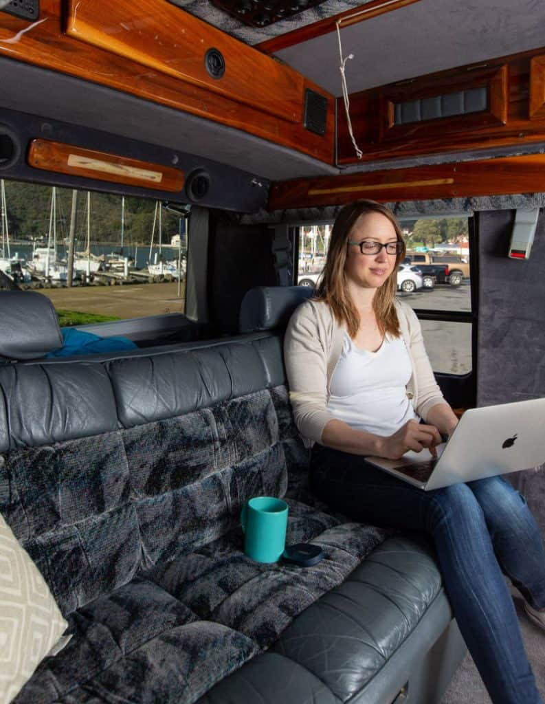 Woman using van life WiFi to work inside a Chevy Astro van