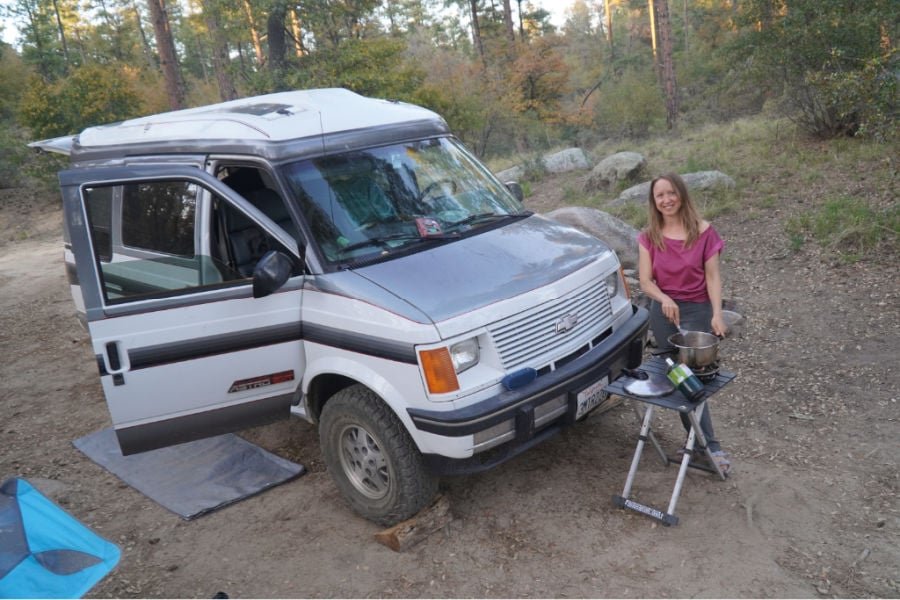Woman using a small folding table as essential boondocking gear outside a campervan