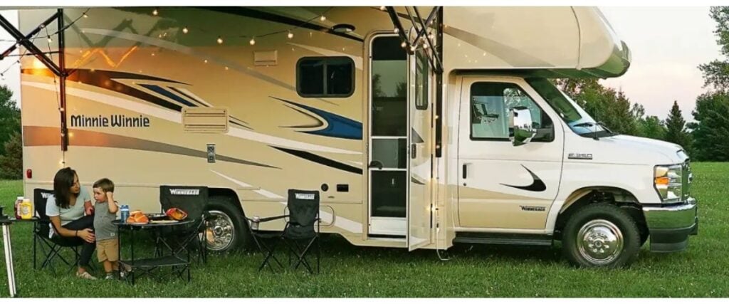 Exterior view of Winnabago Minnie Winnie 26T with mother and child sitting at table