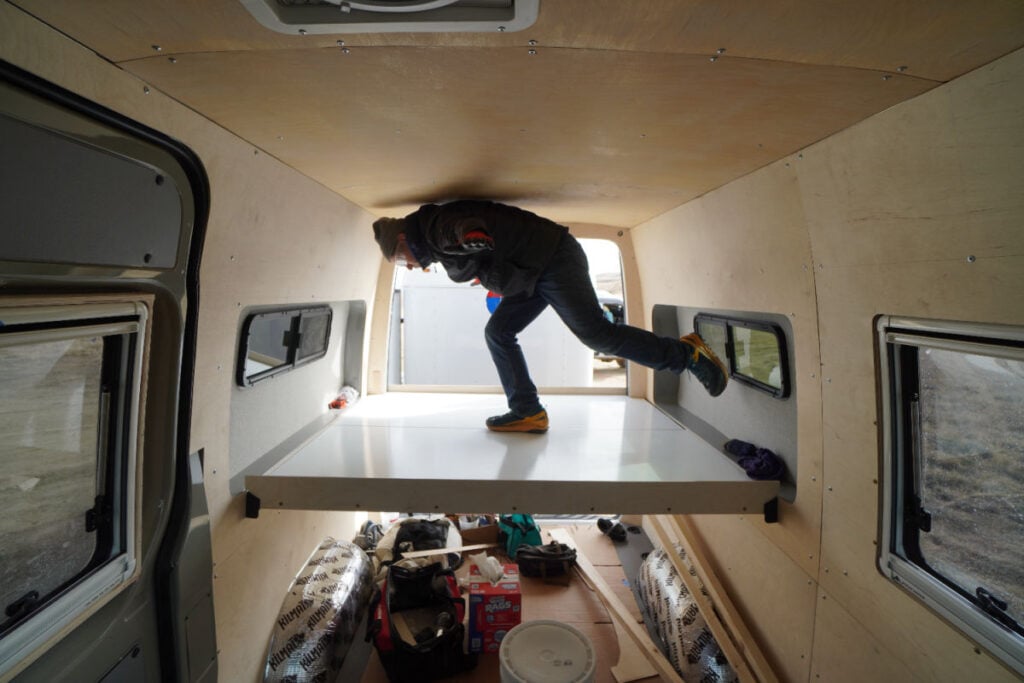 Man standing on campervan bed
