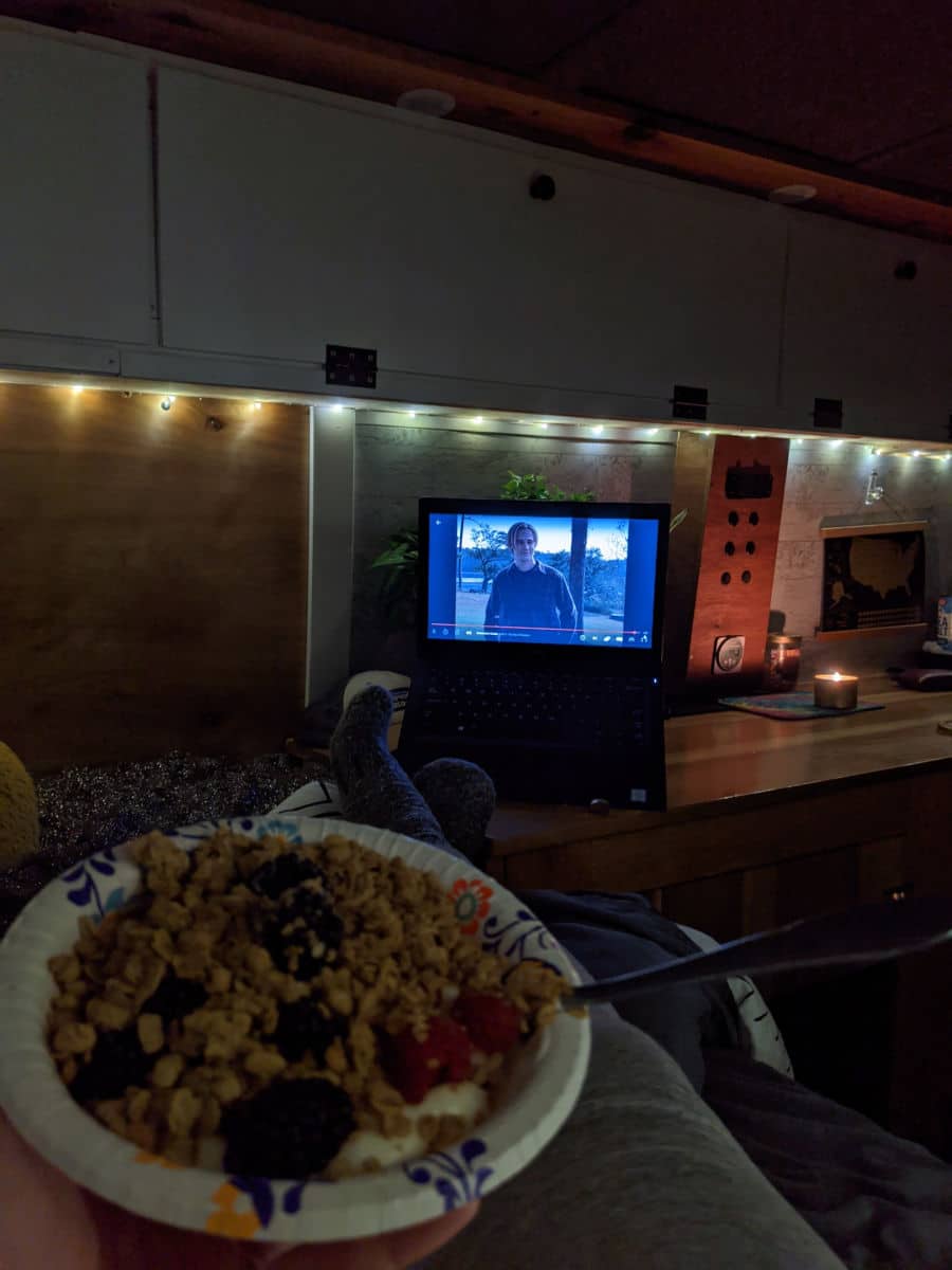 A campervan interior lit with warm lights, a man sitting on the bed