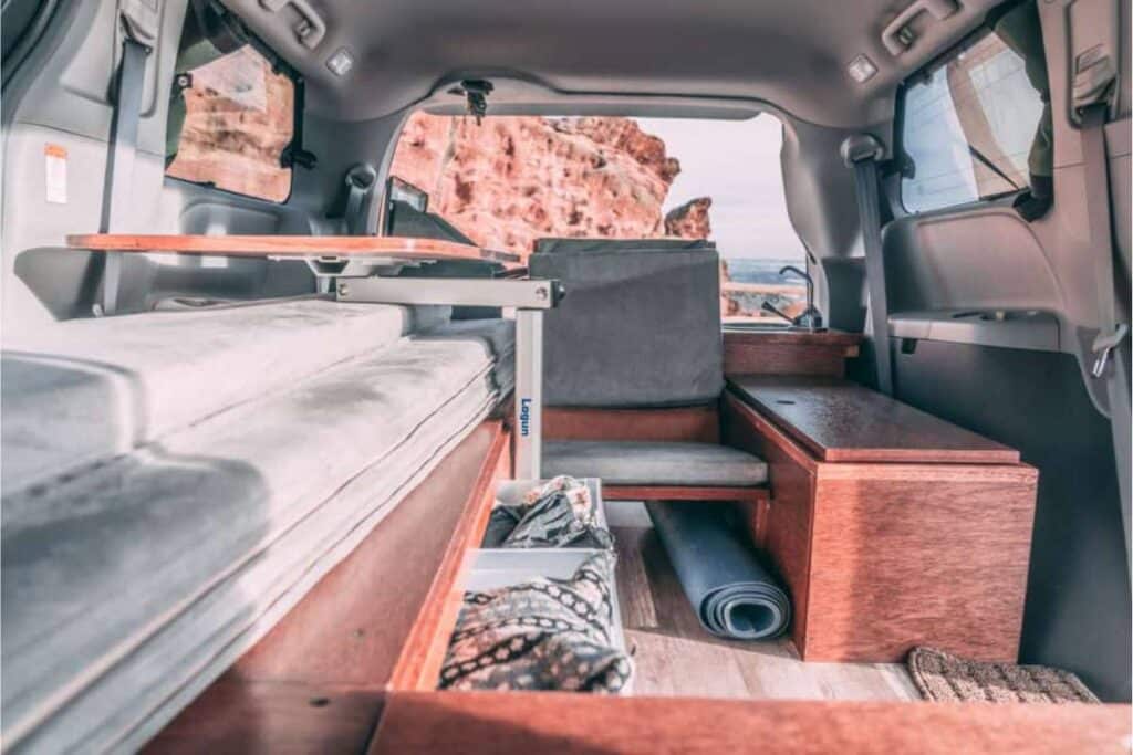 toyota sienna minivan camper showing its interior parked near the beach