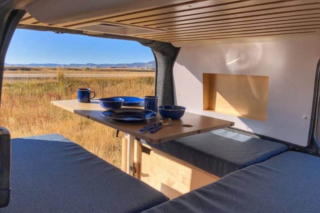 A table set with plates and cups that drops down into a campervan bed