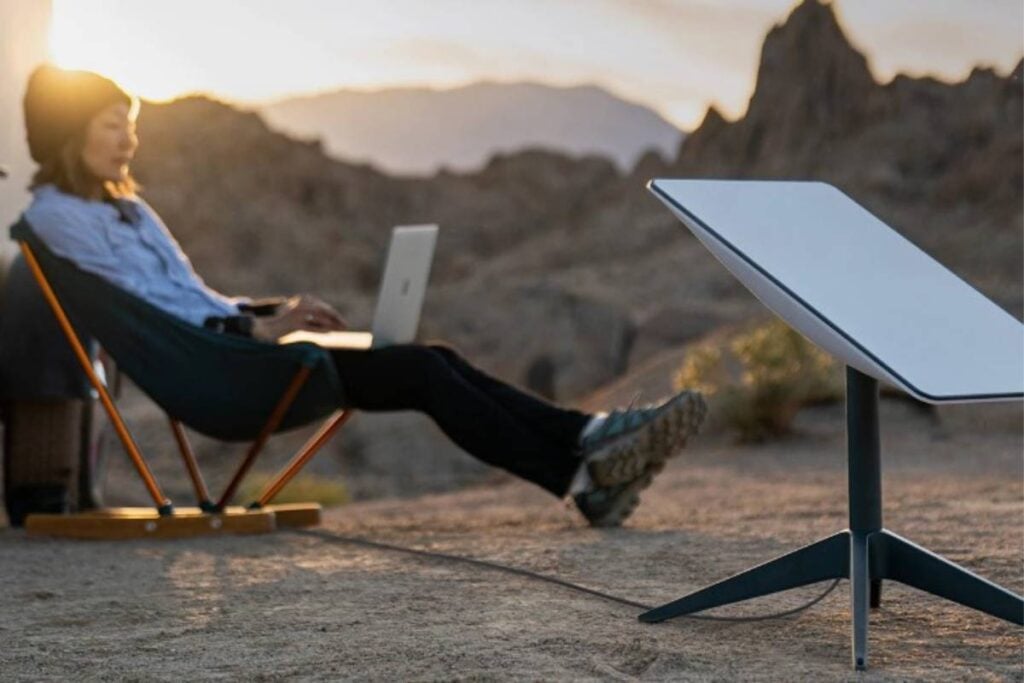 woman using a laptop while sitting on a chair near a starlink roam