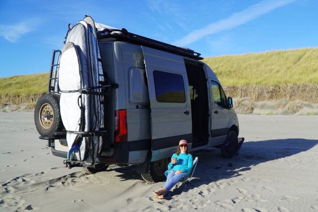 woman sitting next to van on the beach