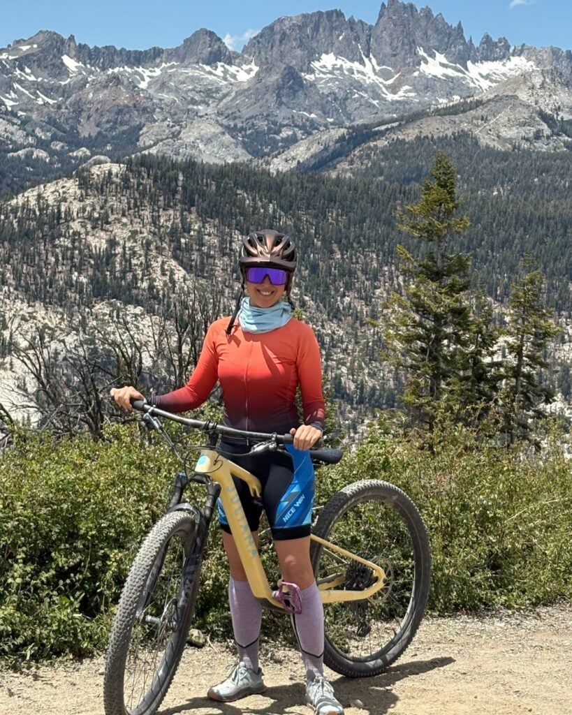 woman with yellow mountain bike in front of mountains