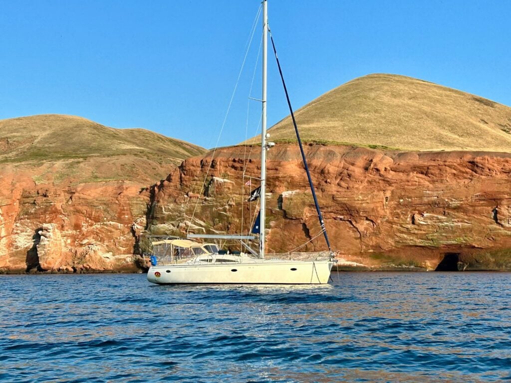 sailboat anchored in front of cliffs