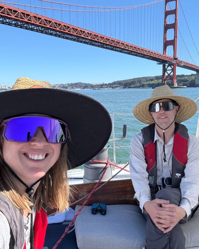 man and woman on sailboat under golden gate