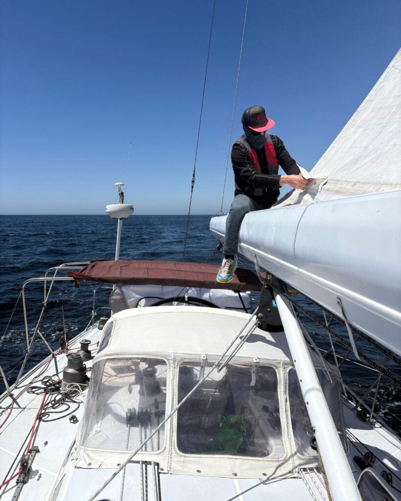 man sitting on sailboat boom