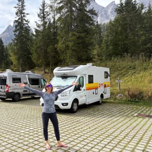 Kristin celebrating next to her campervan rental in the European Alps