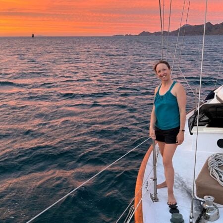 woman standing on deck of boat at sunset