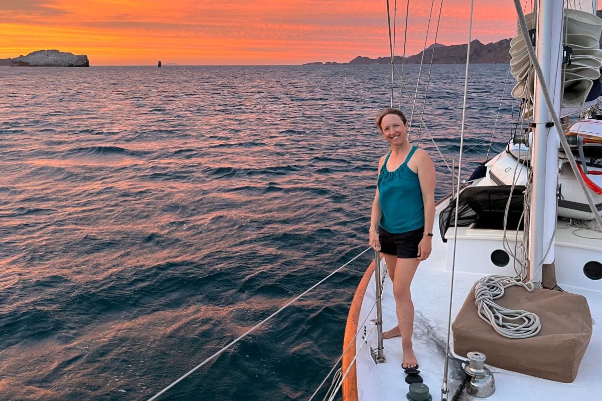 woman standing on deck of boat at sunset