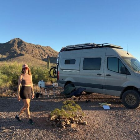 woman walking in front of a sprinter van in the desert