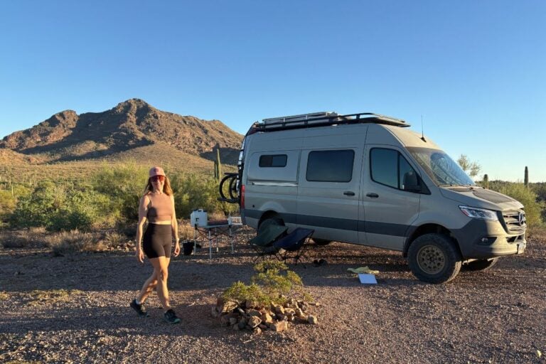 woman walking in front of a sprinter van in the desert