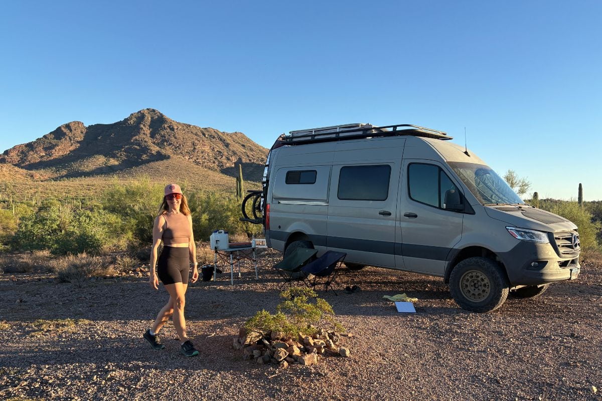 woman walking in front of a sprinter van in the desert
