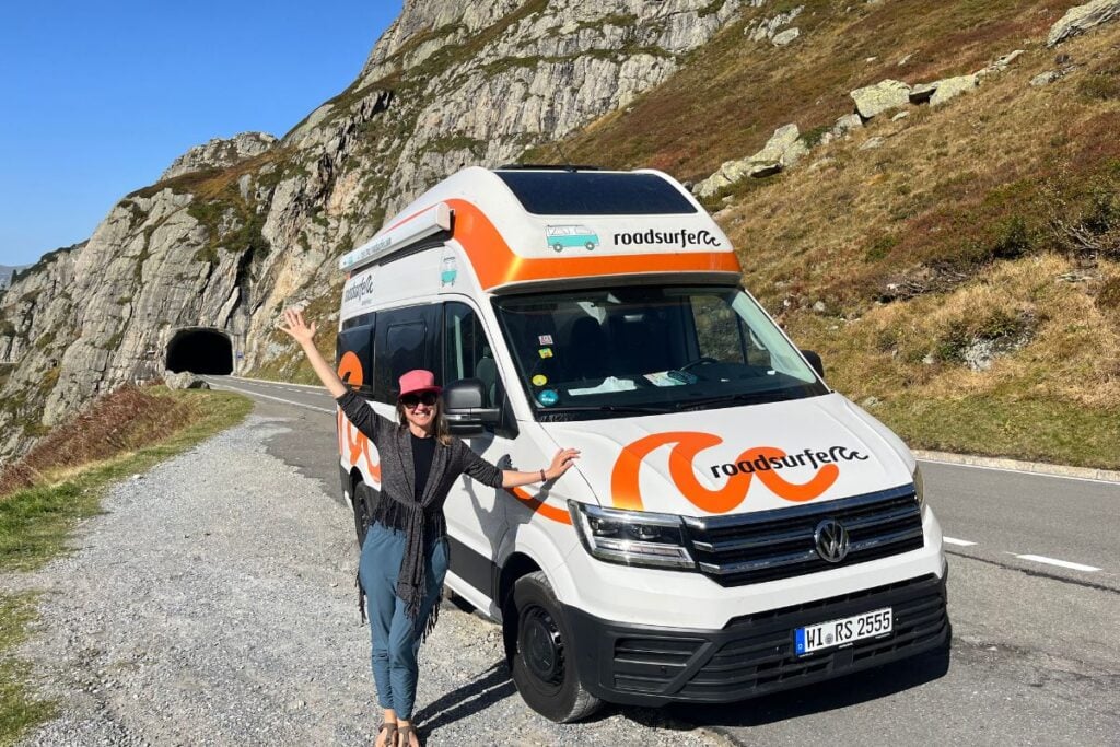 woman standing next to a roadsurfer rental van on a highway