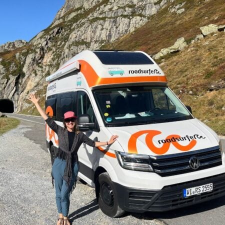 woman standing next to a roadsurfer rental van on a highway