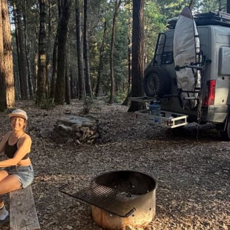 woman working at a picnic table with van in the background