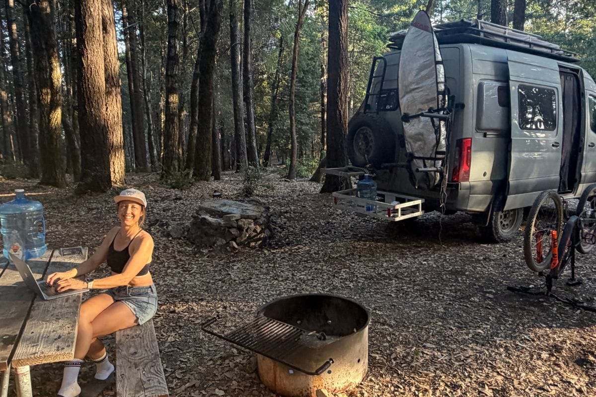 woman working at a picnic table with van in the background
