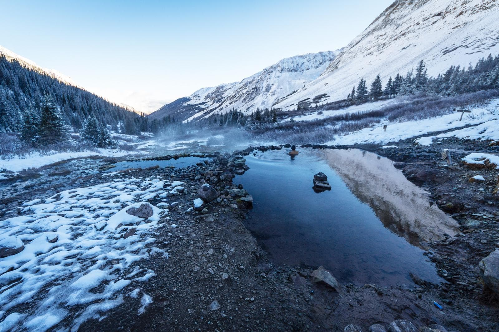 Snow-ringed alpine soaking pool at dawn, peaks behind, Conundrum Hot Springs