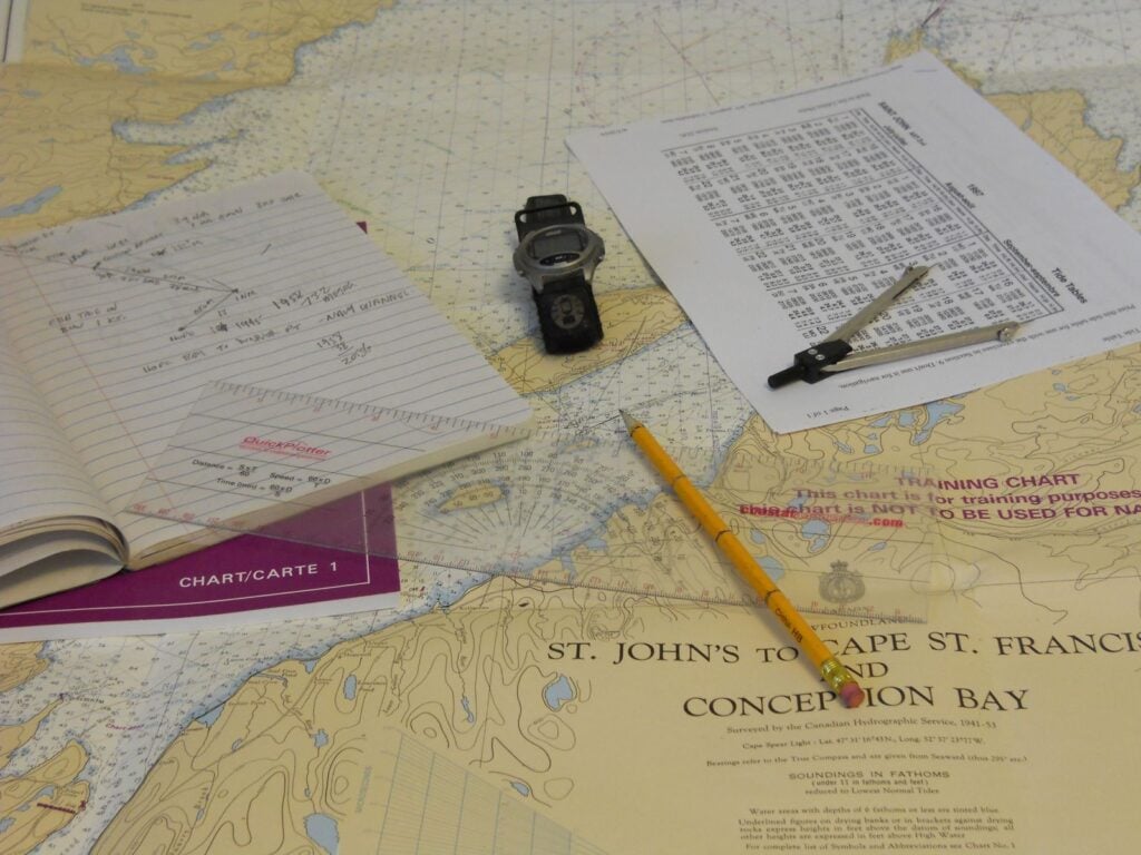 Dead reckoning tools on a nautical chart: dividers, pencil, hand-bearing compass, logbook