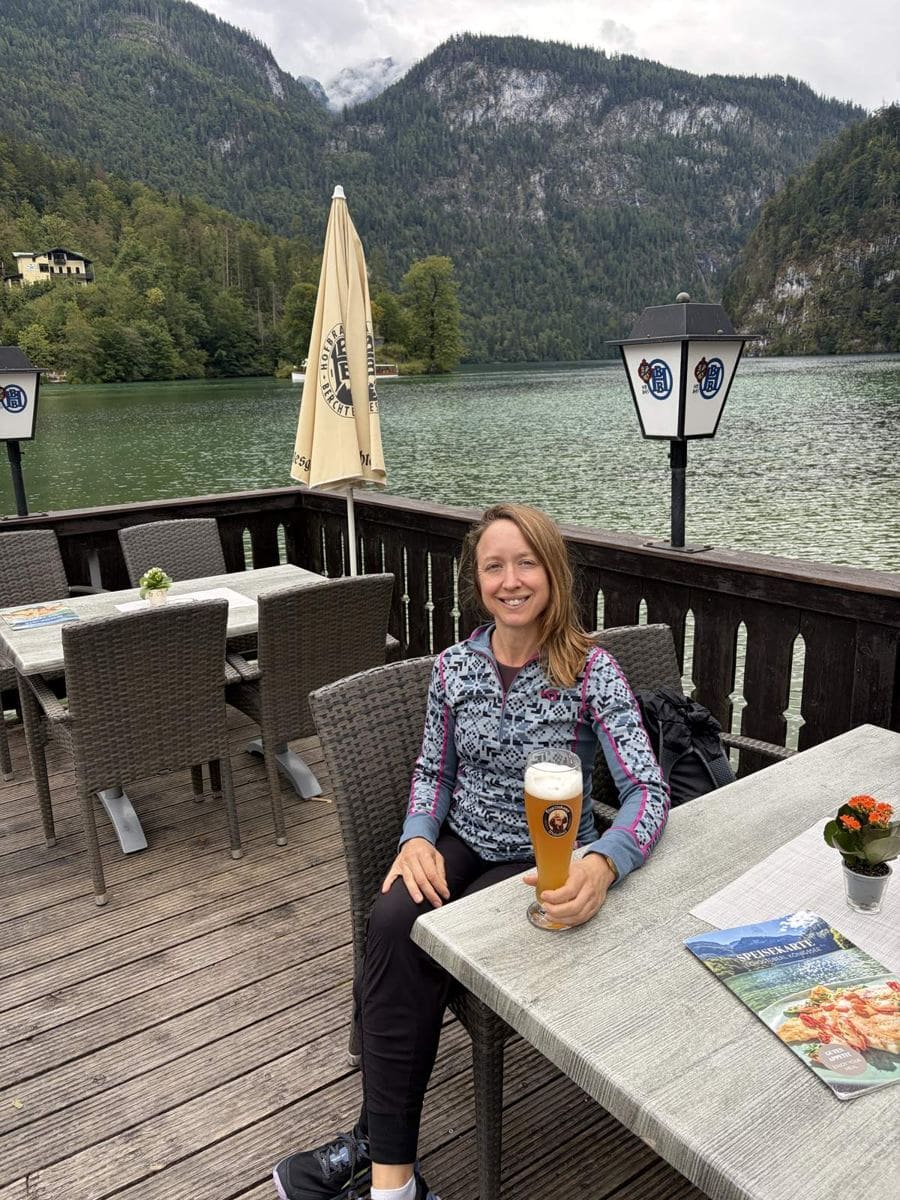 Kristin drinking a wheat beer at a lakeside café on the Königssee with mountains behind
