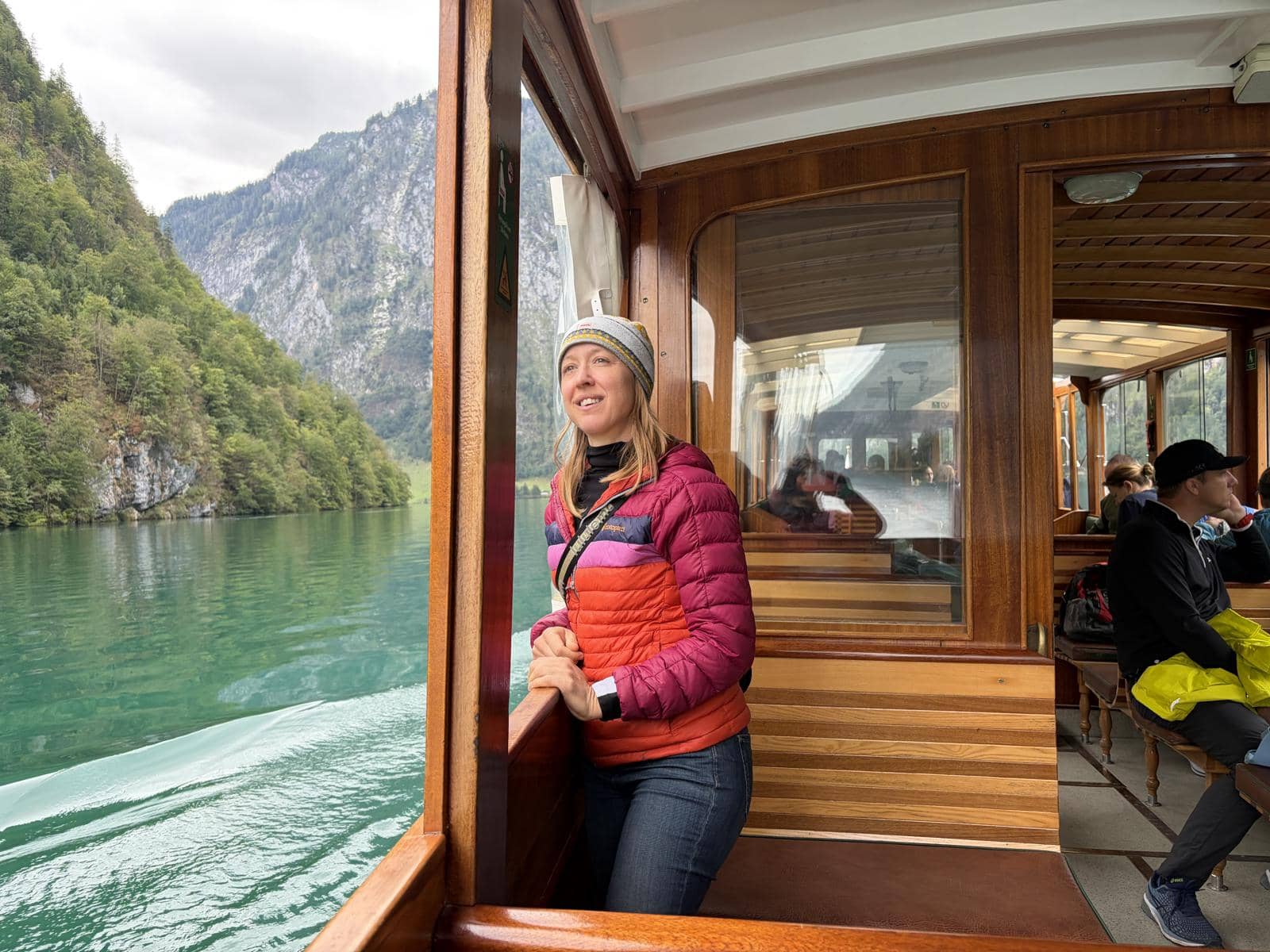 Kristin standing at the open window of an electric boat crossing the Königssee