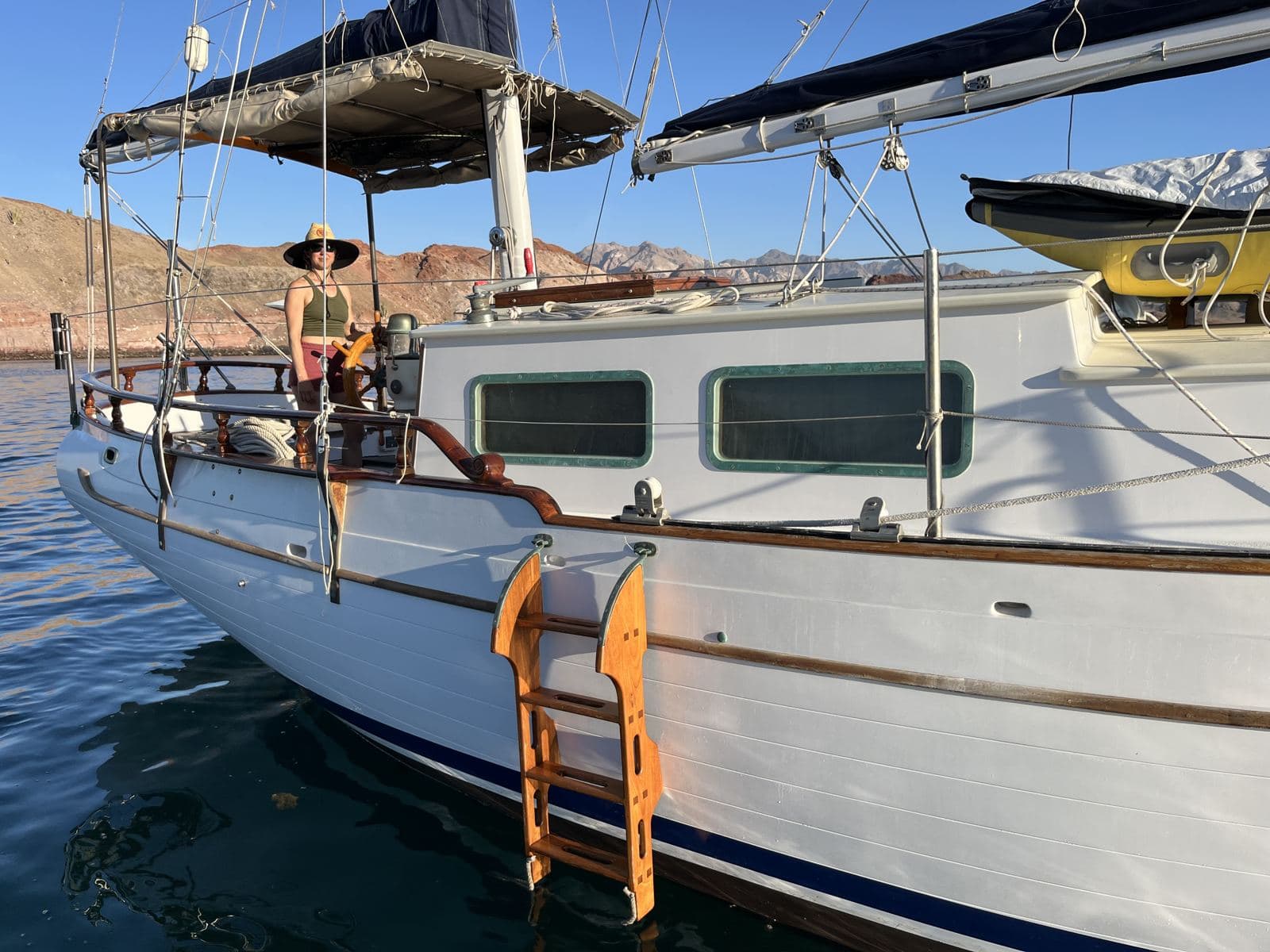 Kristin in a straw hat on the foredeck of a sailboat at anchor in Baja