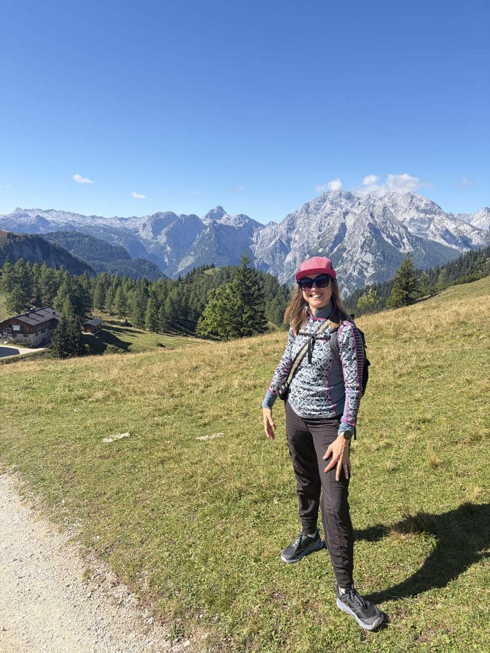 Kristin standing in an alpine meadow on the Jenner with the Watzmann massif behind her