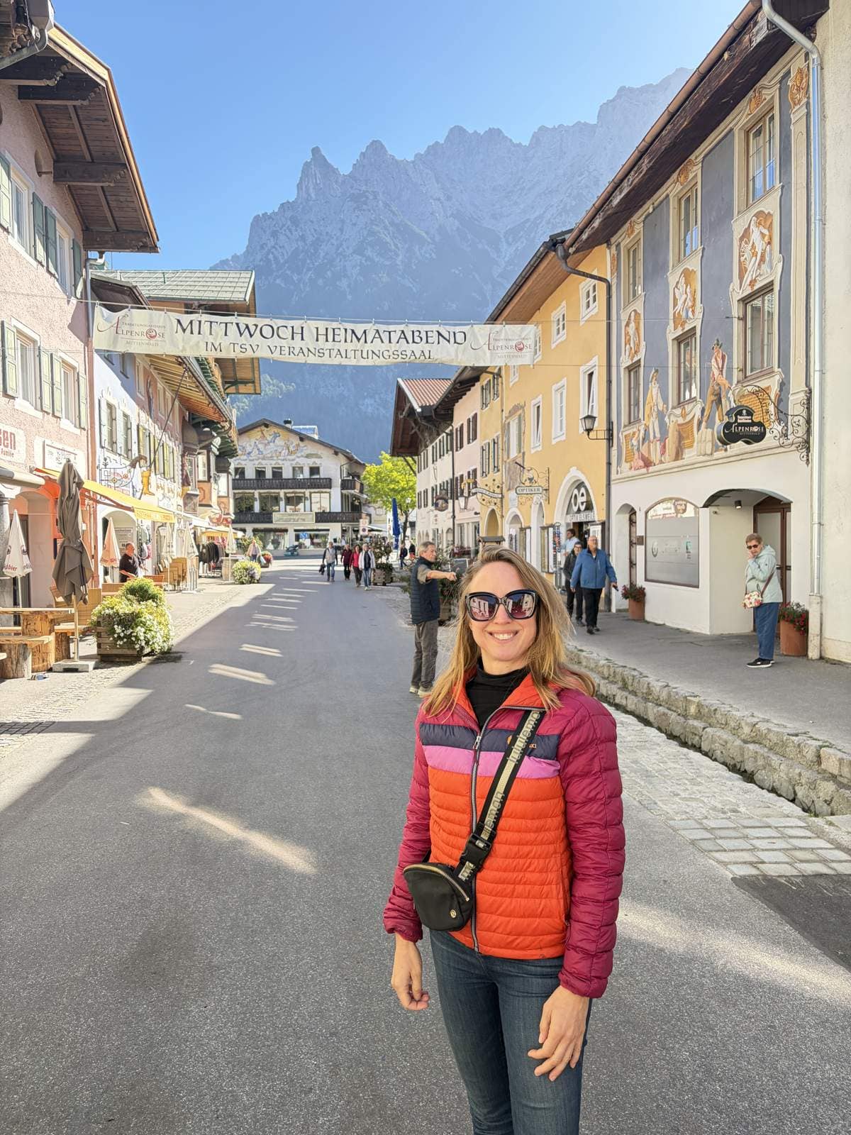Kristin walking down the main street of Mittenwald between painted houses with the Karwendel mountains behind