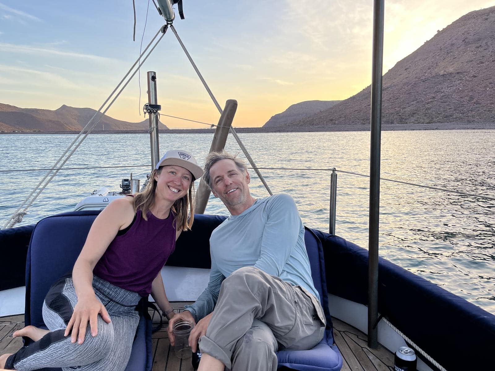 Kristin and Tom sitting in the cockpit of a sailboat at a Baja anchorage at sunset