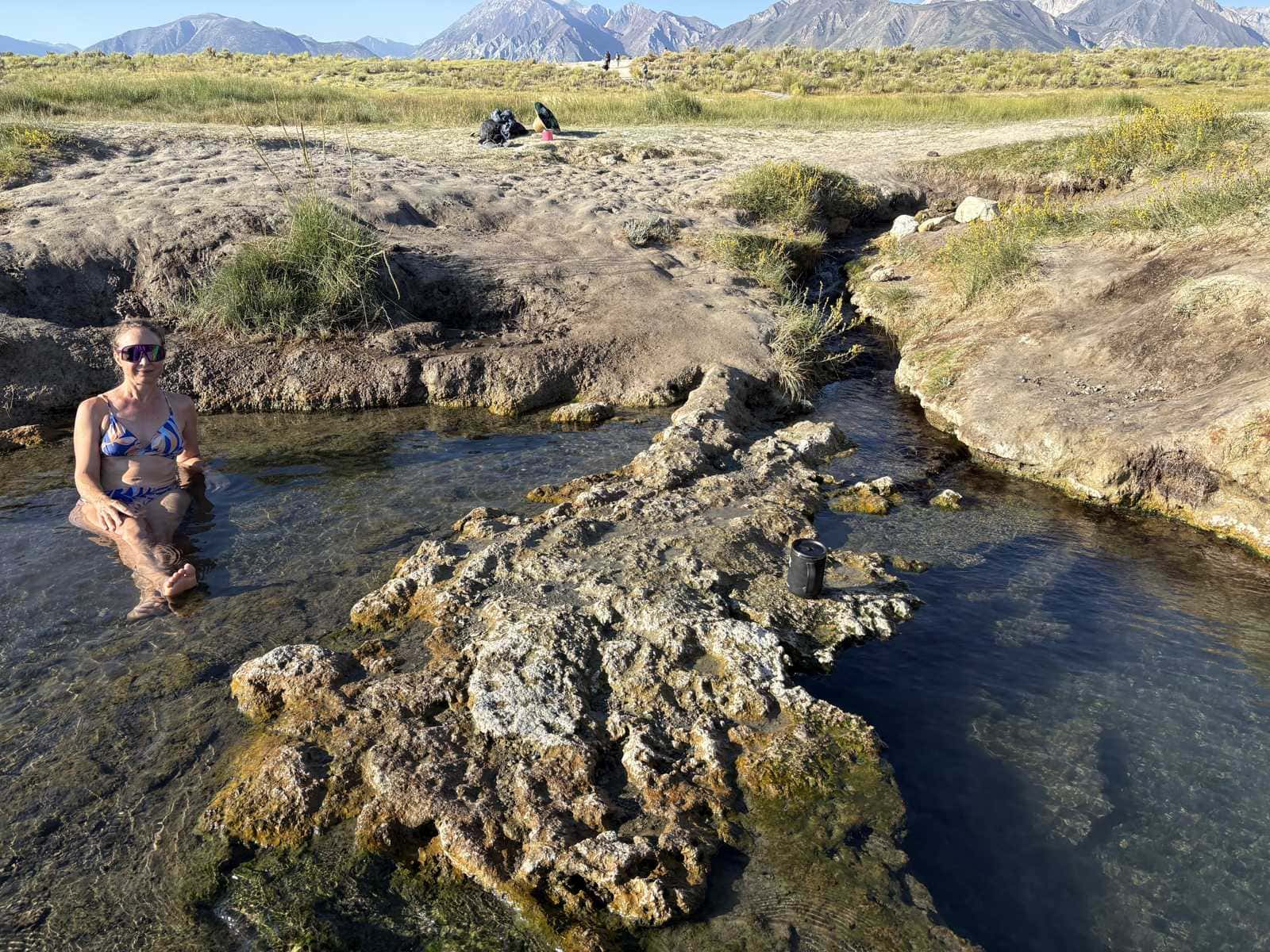 Kristin soaking in a hot creek pool at Wild Willy's Hot Springs in Long Valley near Mammoth Lakes, California, Sierra crest behind