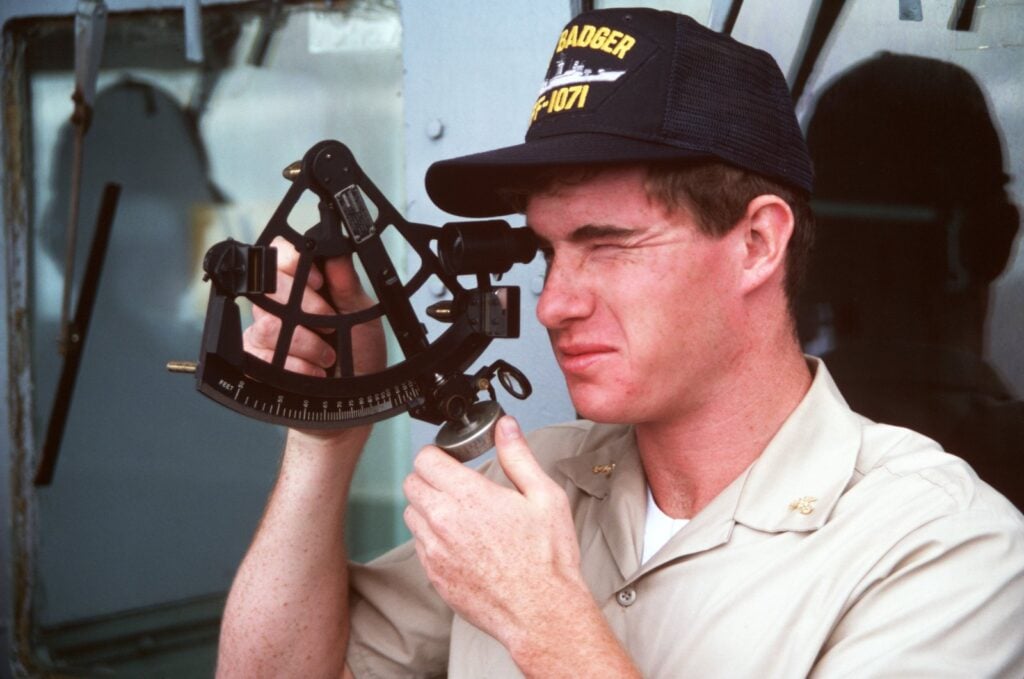 A navigator taking a sextant reading at sea