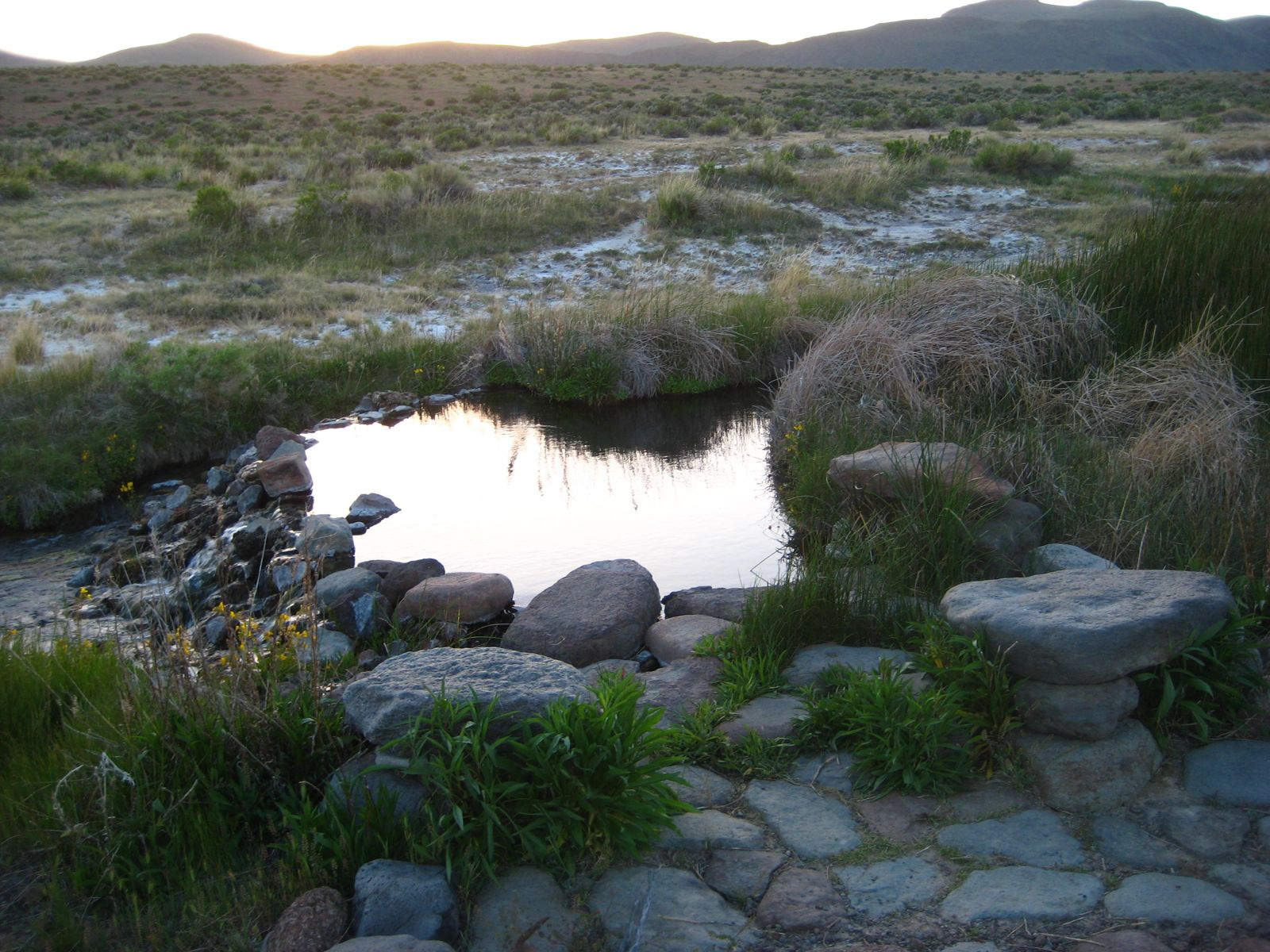 Rock-rimmed pool at dusk with sagebrush flats and hills, Soldier Meadows