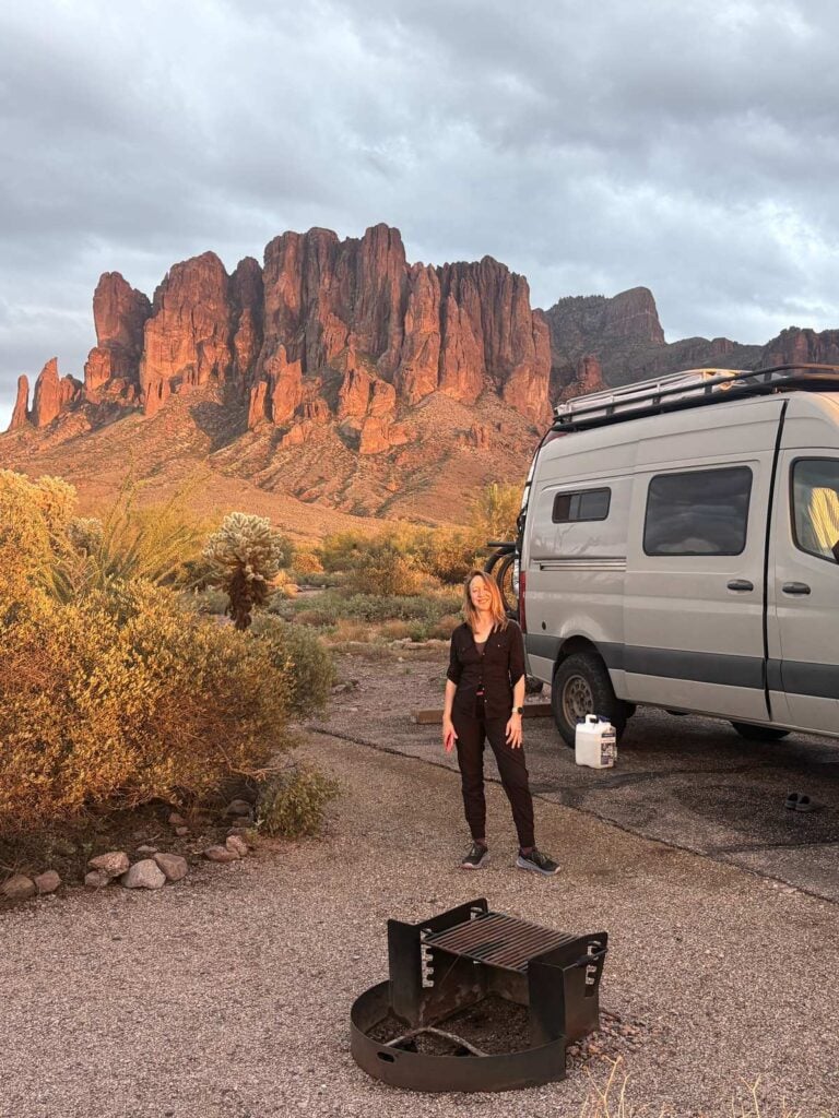 Kristin Hanes at her van's campsite at sunset in the Arizona desert, fire ring in front