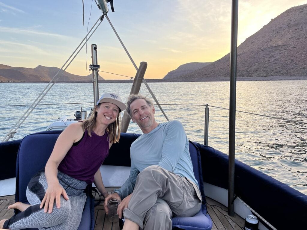Kristin Hanes and Tom in the cockpit of their sailboat at a Baja anchorage at sunset