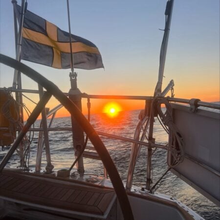 The Swedish flag flying off a sailboat's stern at sunset