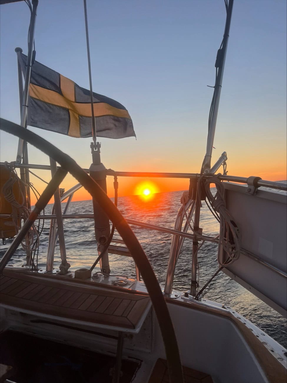The Swedish flag flying off a sailboat's stern at sunset