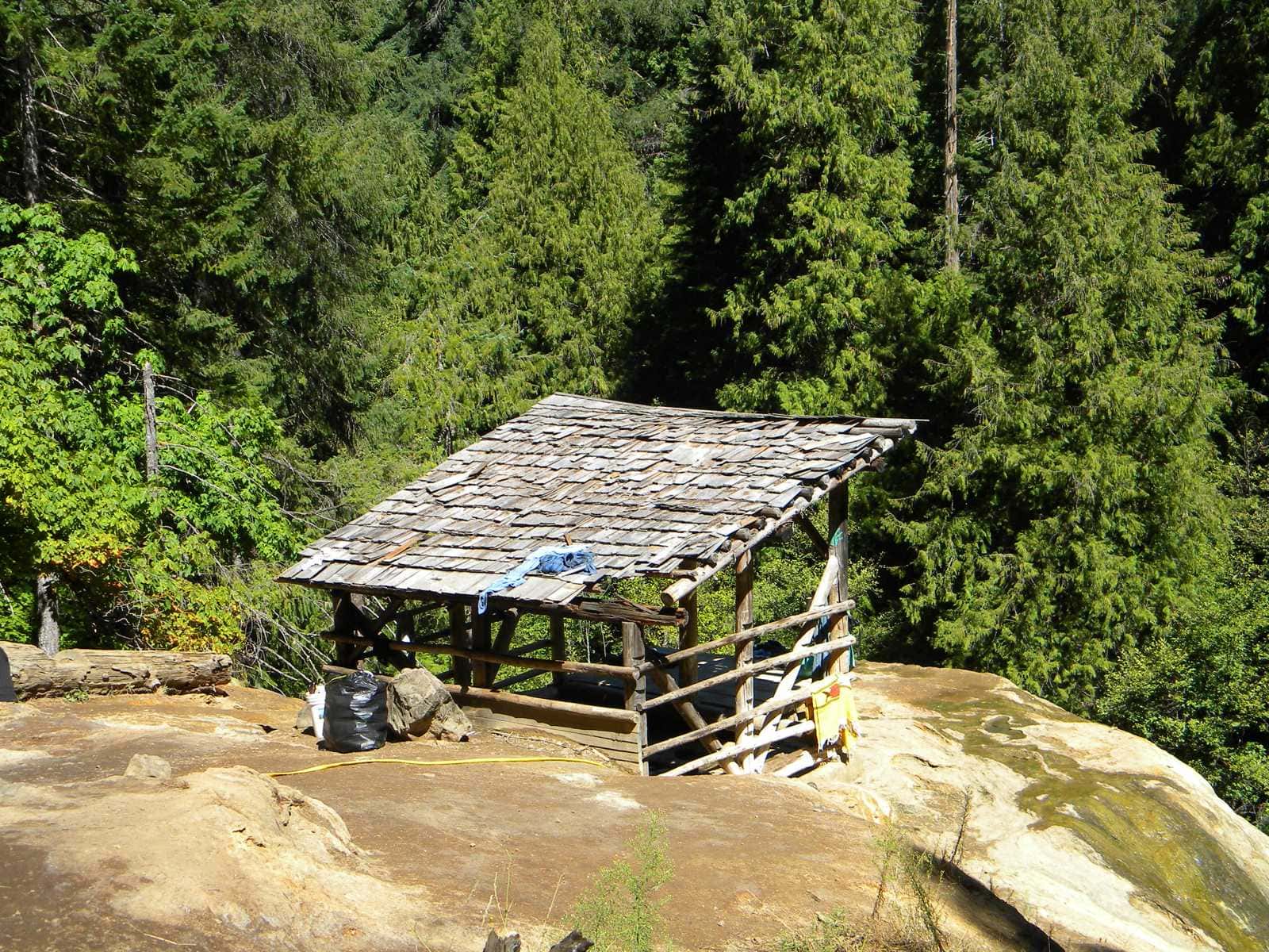 Cedar-shake shelter over the upper pool on the travertine ledge, forest behind, Umpqua Hot Springs